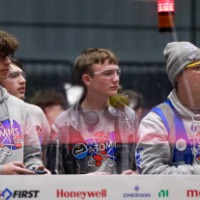 Three teammates watch their robot on the field
